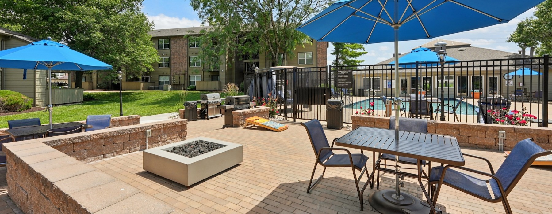 a patio with a fire pit, table and chairs